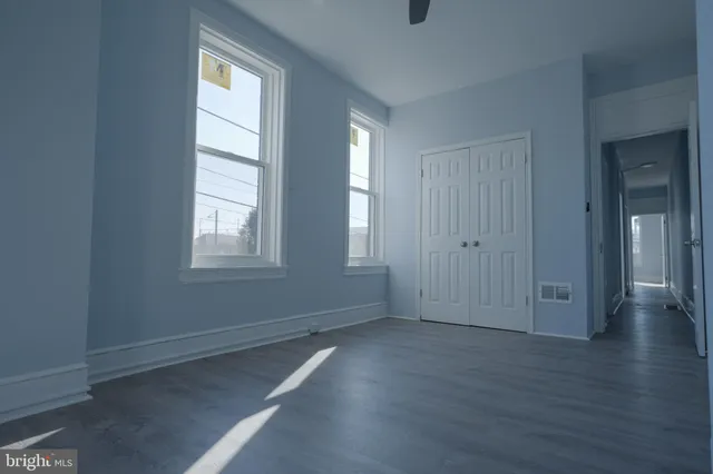 an empty room with wooden floor and windows