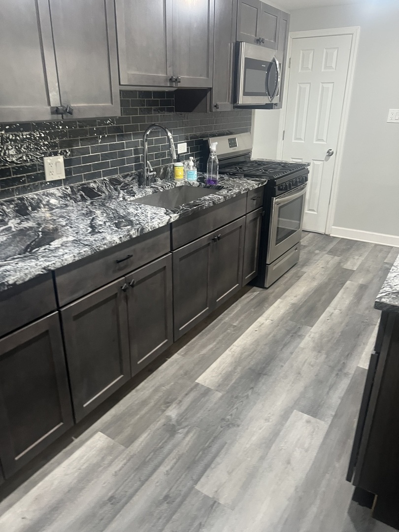 4740 South Prairie Avenue, Unit G Chicago, IL 60615 - Photo 2 of 9 a kitchen with stainless steel appliances granite countertop a sink stove and cabinets