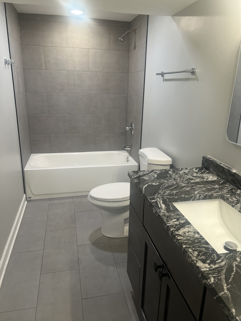 4740 South Prairie Avenue, Unit G Chicago, IL 60615 - Photo 5 of 9 a bathroom with a granite countertop bathtub sink vanity mirror and toilet