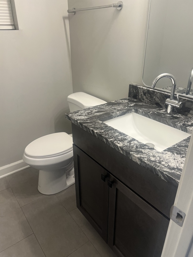 4740 South Prairie Avenue, Unit G Chicago, IL 60615 - Photo 6 of 9 a bathroom with a granite countertop sink a toilet and a mirror