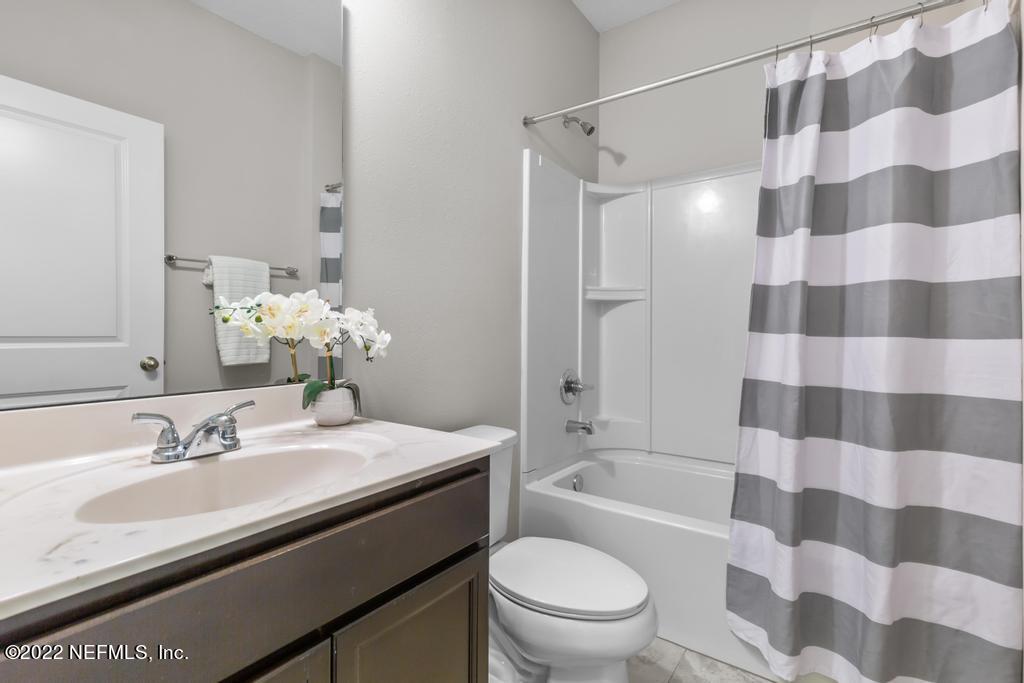 9802 Kevin Road Jacksonville, FL 32257 - Photo 17 of 22 a bathroom with a sink a toilet a mirror and shower