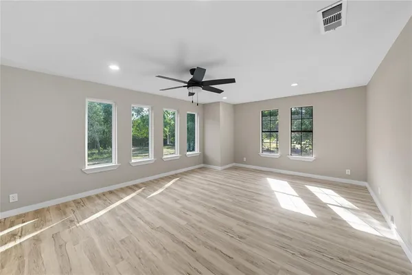 a view of an empty room with a window and wooden floor