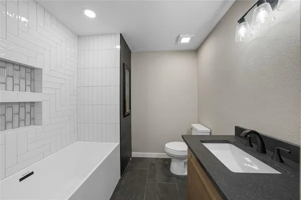 a bathroom with a tub sink toilet and a mirror