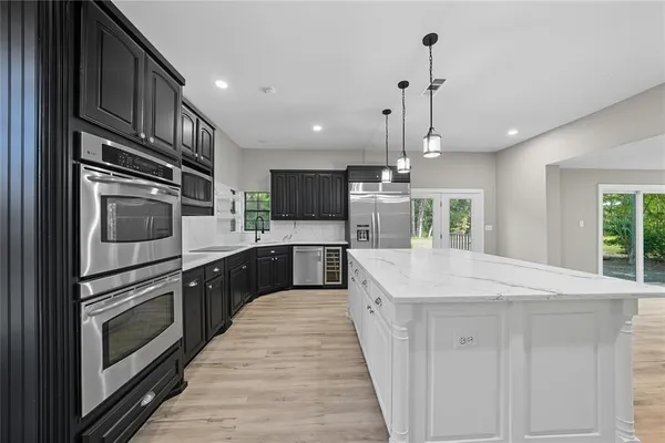 a large kitchen with stainless steel appliances kitchen island granite countertop a stove top oven a sink dishwasher a dining table and chairs with wooden floor