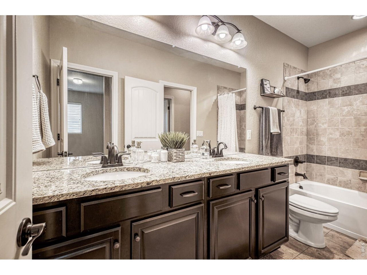 7992 St Street Frederick, CO 80530 - Photo 21 of 28 a bathroom with a granite countertop sink a toilet a mirror a bathtub and shower