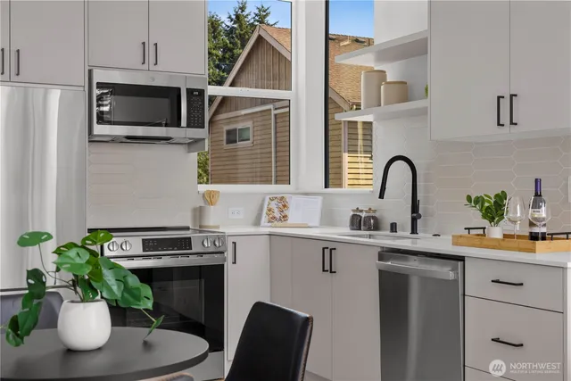 a kitchen with stainless steel appliances a sink a microwave a stove and white cabinets