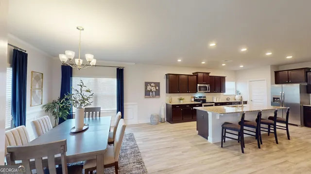 a kitchen with kitchen island granite countertop a dining table chairs stainless steel appliances and cabinets