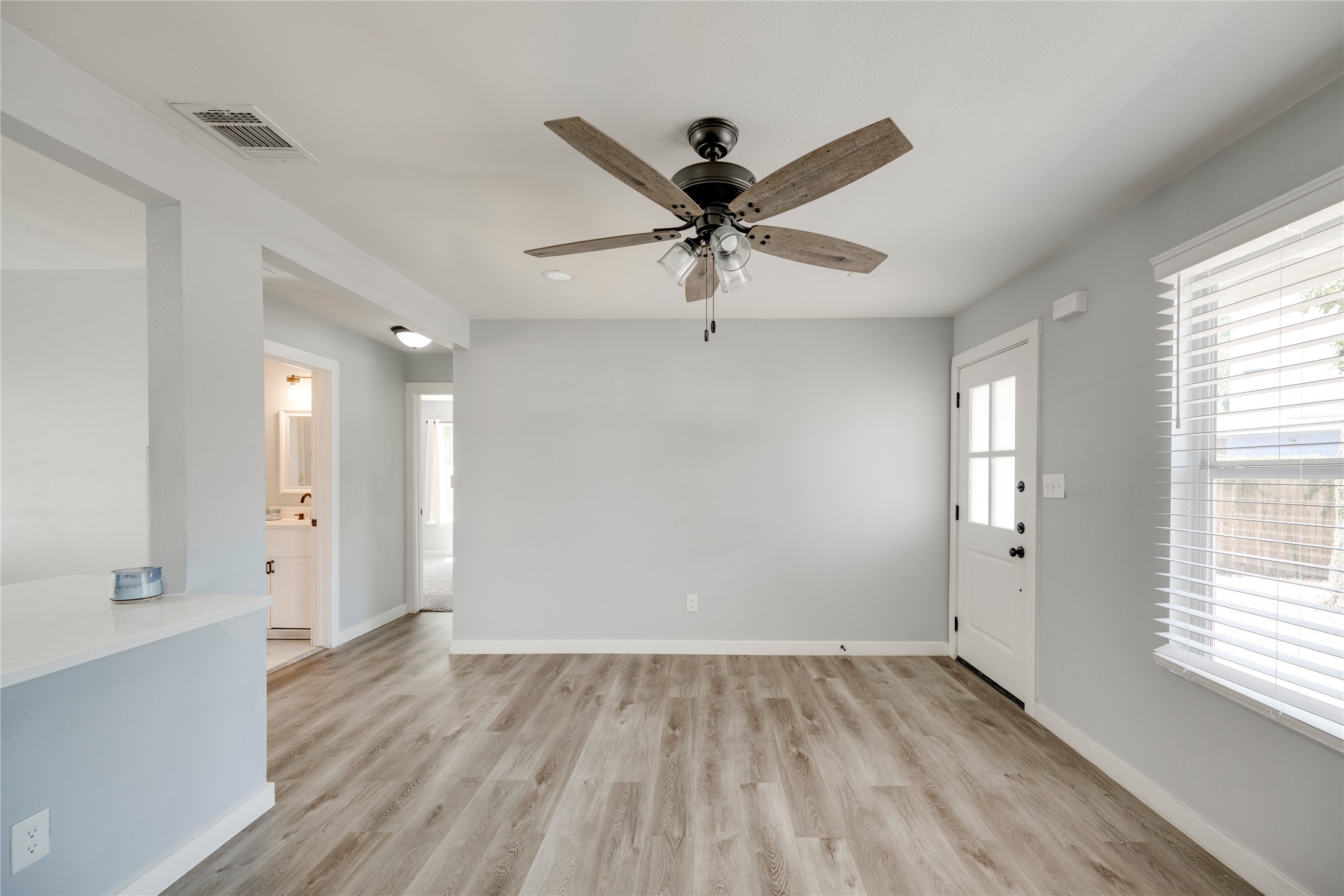 1400 Marcus Place, Unit B Austin, TX 78721 - Photo 19 of 39 A well-lit living area features warm wood flooring and a modern ceiling fan, offering comfortable living.