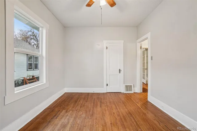 an empty room with a hardwood and ceiling fan
