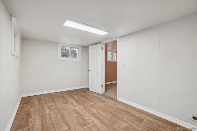 an empty room with wooden floor and window