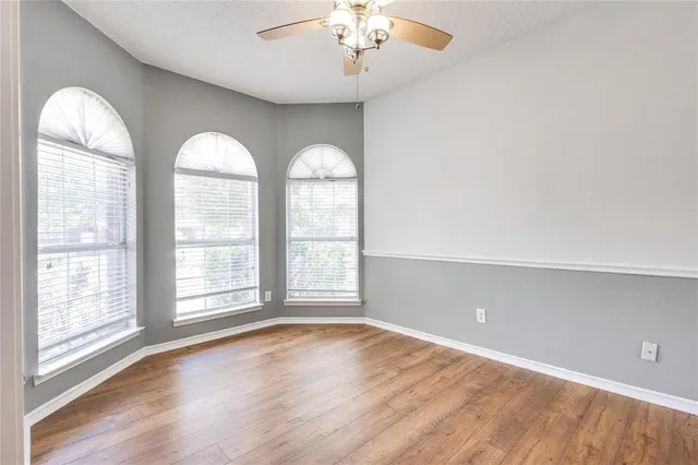 an empty room with wooden floor chandelier and glass door