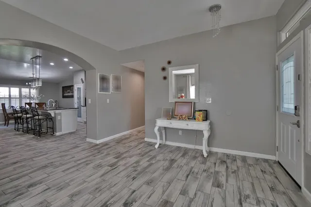 a kitchen with stainless steel appliances kitchen island granite countertop a dining table chairs refrigerator and sink