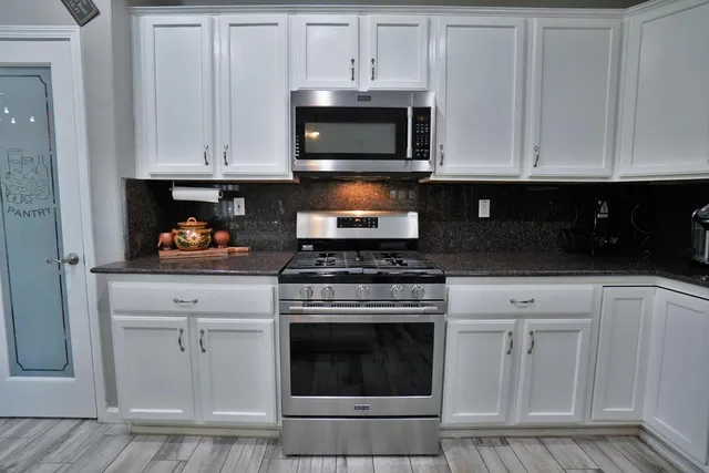 a kitchen with granite countertop a refrigerator and a stove top oven