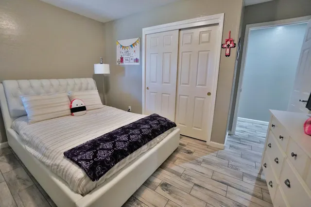 a view of a hallway with wooden floor and a bathroom