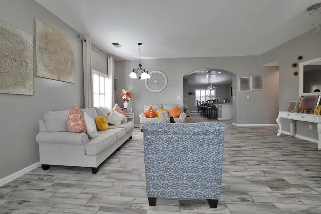 a living room with furniture kitchen view and a chandelier