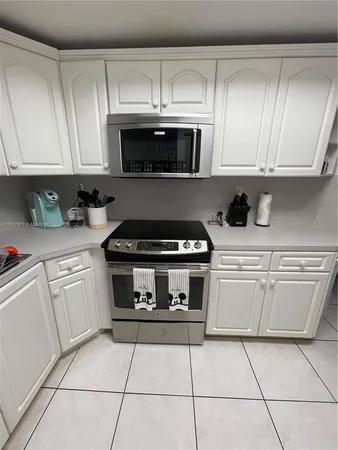 a kitchen with granite countertop white cabinets and appliances