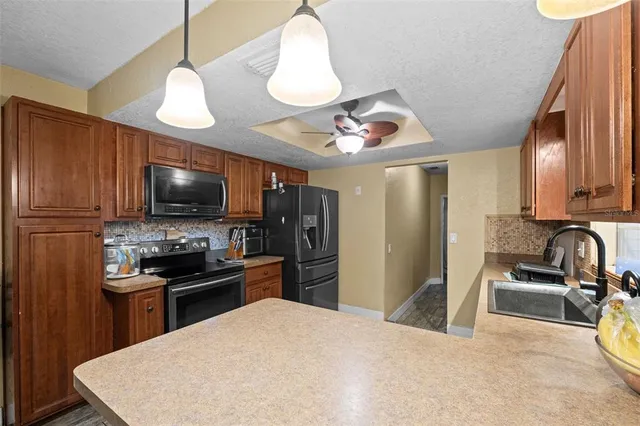 a kitchen with stainless steel appliances granite countertop a sink dishwasher a stove and a refrigerator with wooden floor