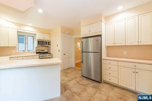 a kitchen with white cabinets and refrigerator