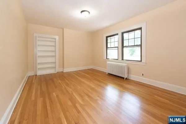 an empty room with wooden floor closet and windows