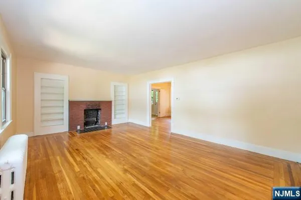 a view of empty room with wooden floor and fireplace