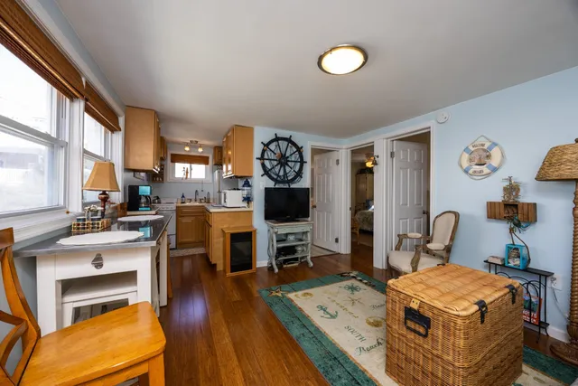 a room with stainless steel appliances kitchen island granite countertop a stove a sink a dining table and chairs with wooden floor