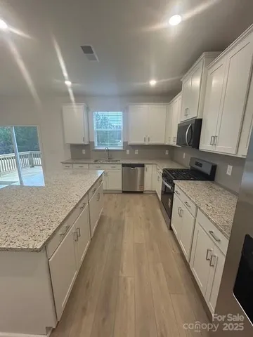 a large kitchen with stainless steel appliances granite countertop a lot of counter space and wooden floors