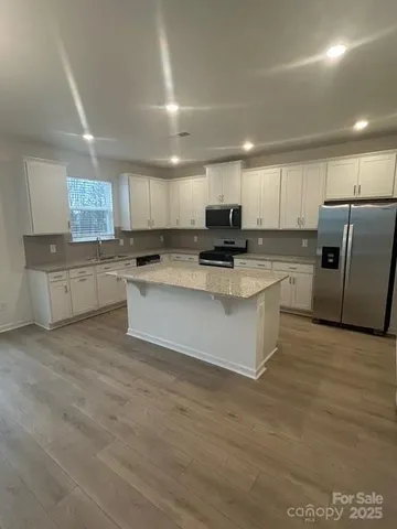 a kitchen with stainless steel appliances granite countertop a stove a sink a refrigerator white cabinets and a refrigerator