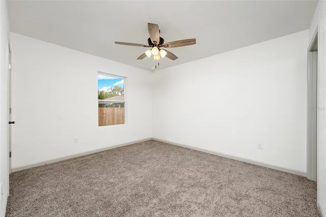 an empty room with a window and a ceiling fan