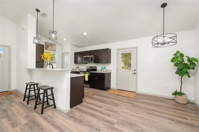 a kitchen with stainless steel appliances granite countertop a refrigerator a microwave a dining table and chairs