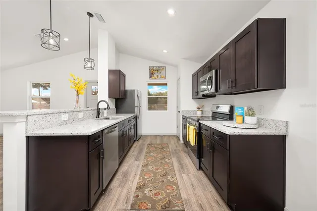 a kitchen with stainless steel appliances granite countertop a sink stove and cabinets