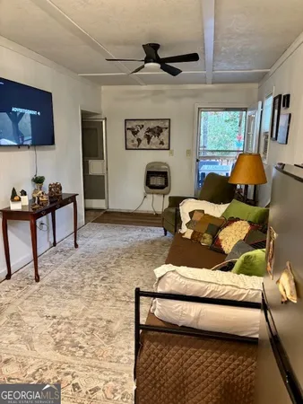 a bedroom with a bed a standing fan and a bookshelf