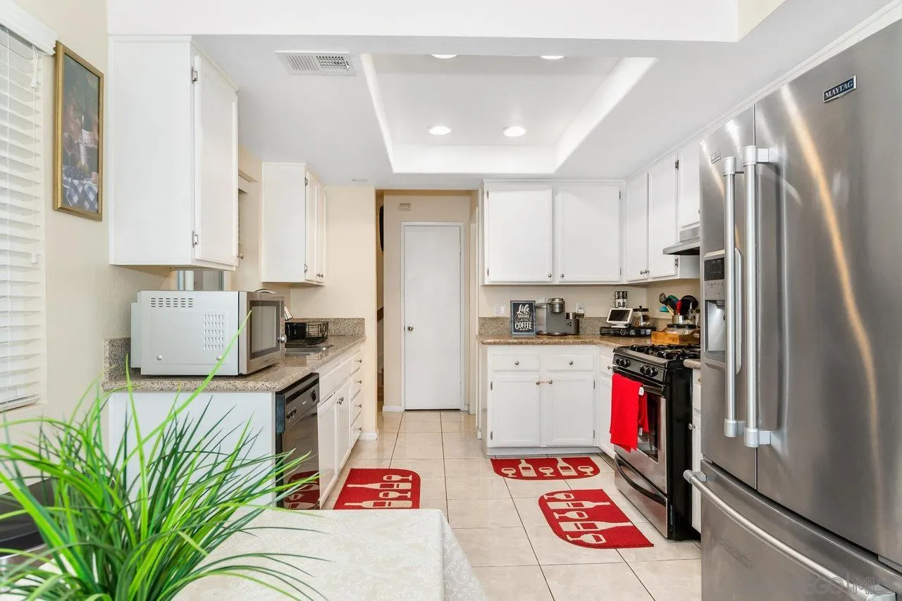 1458 Summit Drive Chula Vista, CA 91910 - Photo 9 of 22 a kitchen with stainless steel appliances kitchen island granite countertop a refrigerator and a stove top oven