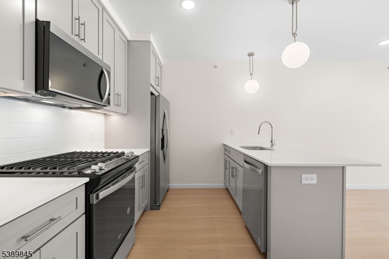 a kitchen with stainless steel appliances a stove microwave and sink