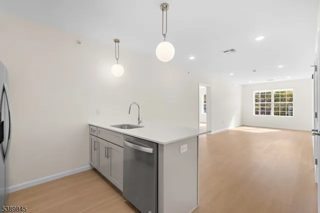 a view of a kitchen with a sink and dishwasher with wooden floor