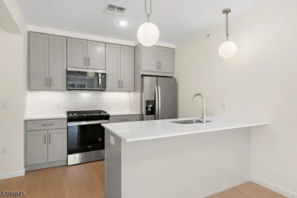a kitchen with stainless steel appliances granite countertop a sink a stove a refrigerator a center island with wooden floor