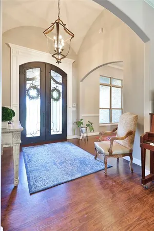 a dining room with wooden floor a chandelier a wooden table and chairs