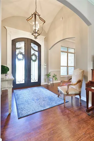 a dining room with wooden floor a chandelier a wooden table and chairs