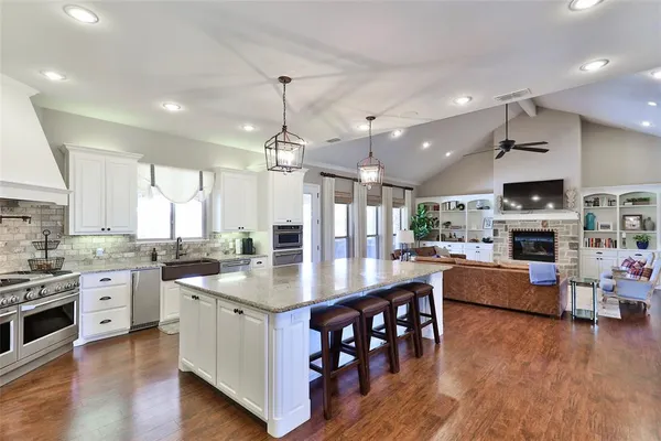 a kitchen with stainless steel appliances granite countertop a kitchen island hardwood floor a stove and a sink