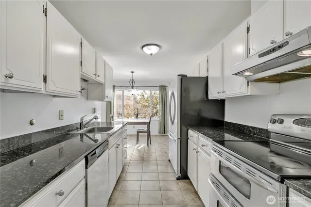a kitchen with granite countertop a sink a counter space stainless steel appliances and cabinets
