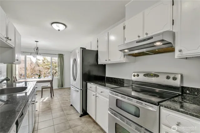 a kitchen with stainless steel appliances granite countertop a sink a stove a refrigerator and cabinets