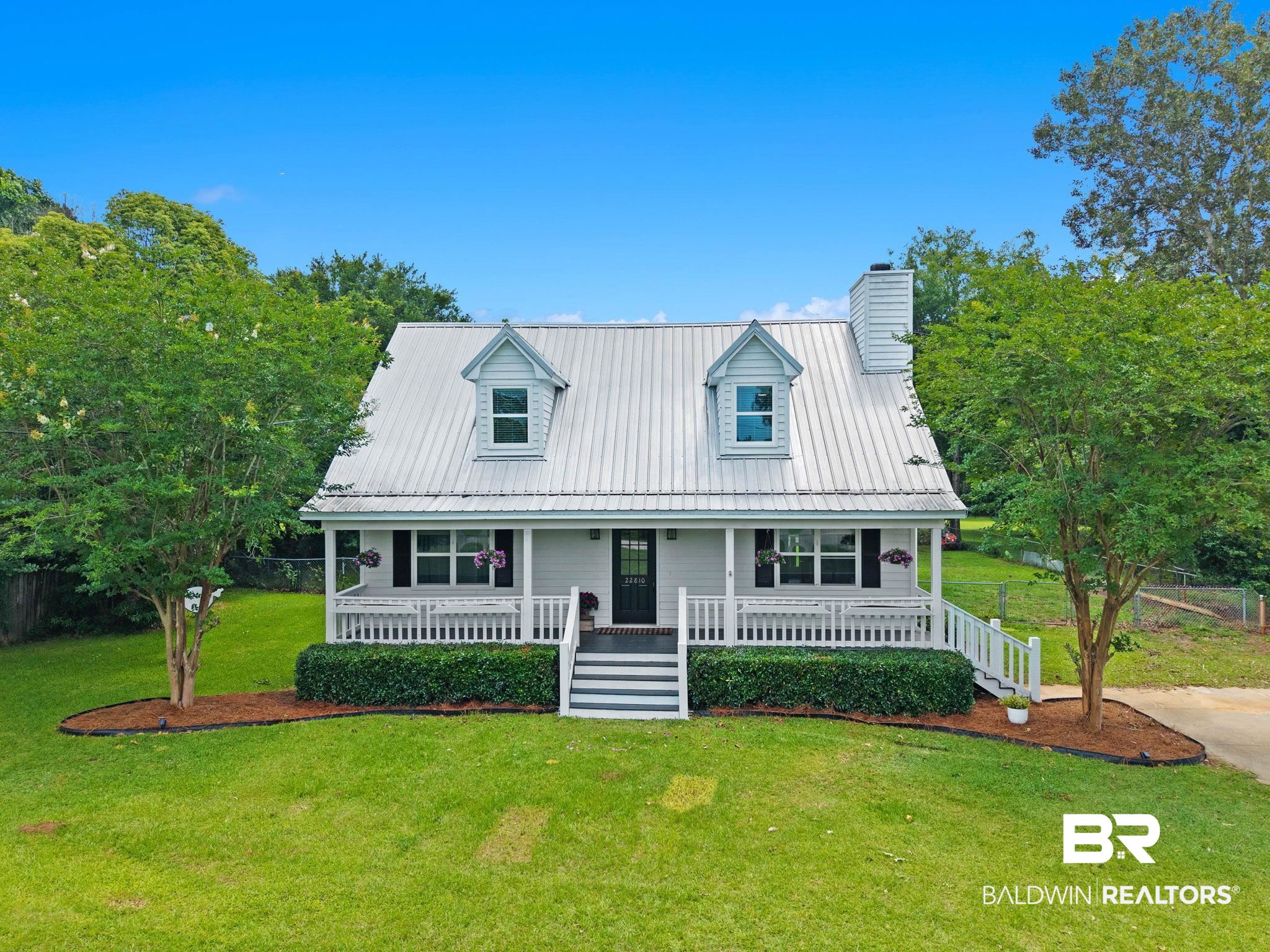 22810 High Ridge Road Fairhope, AL 36532 - Photo 1 of 78 Charming cottage-style home featuring a covered front porch with white railings, a metal roof, two dormer windows, and a prominent chimney