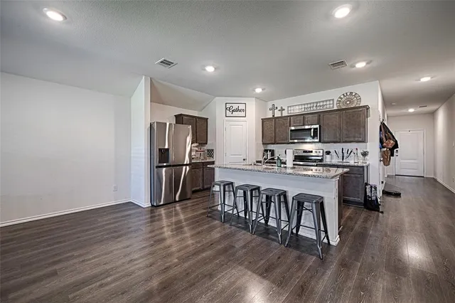 a kitchen with stainless steel appliances a microwave a stove a sink a refrigerator and wooden floor