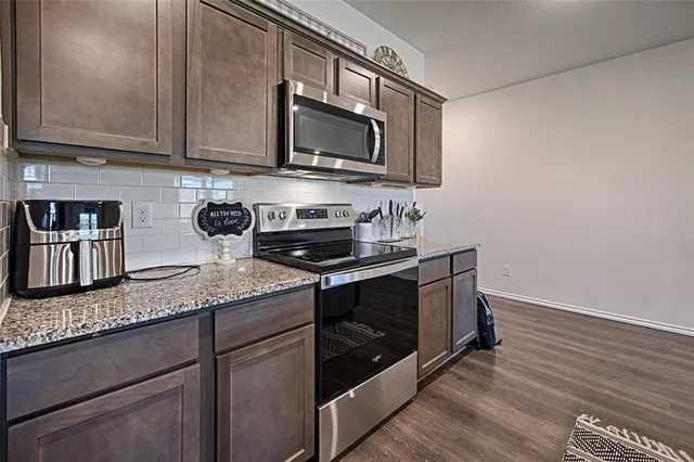 a kitchen with stainless steel appliances granite countertop a sink a stove a microwave and cabinets