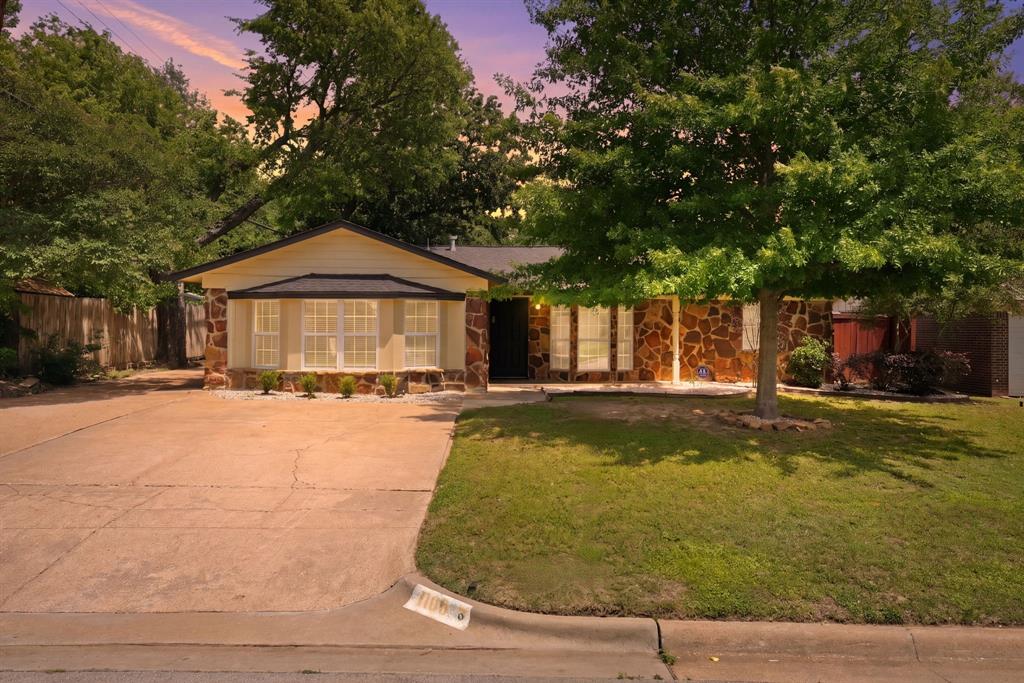 Ranch-style exterior featuring stone veneer siding, a bay window with multiple panes, and a concrete driveway