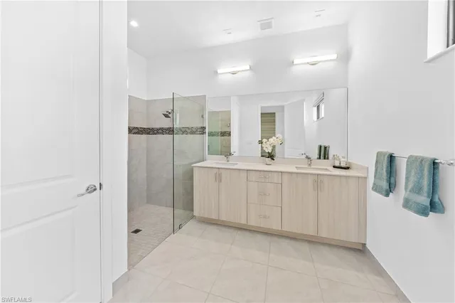 a bathroom with a double vanity sink mirror and shower