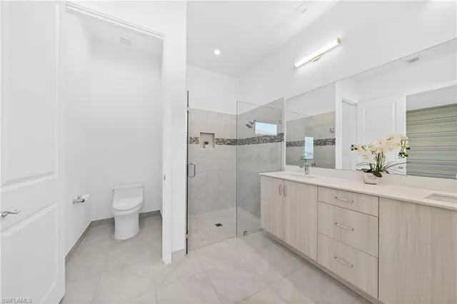 a spacious bathroom with a double vanity sink a toilet and a shower