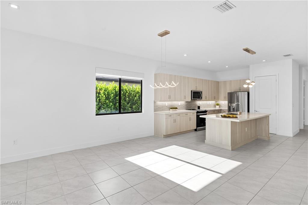 4947 Brigata Way Avenue Immokalee, FL 34142 - Photo 8 of 50 a large white kitchen with a large window a oven a counter space and stainless steel appliances