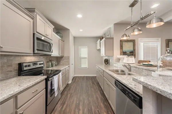 a large kitchen with stainless steel appliances granite countertop a lot of counter space a sink and dishwasher a stove top oven with wooden floor