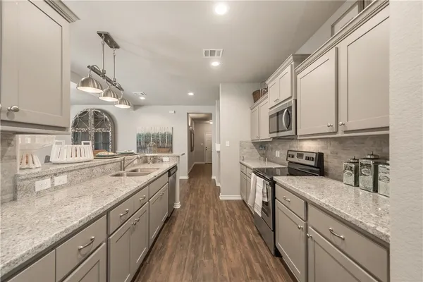 a large kitchen with stainless steel appliances granite countertop a lot of counter space and wooden floor