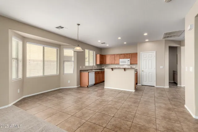 a view of a kitchen with kitchen island wooden floors stainless steel appliances windows